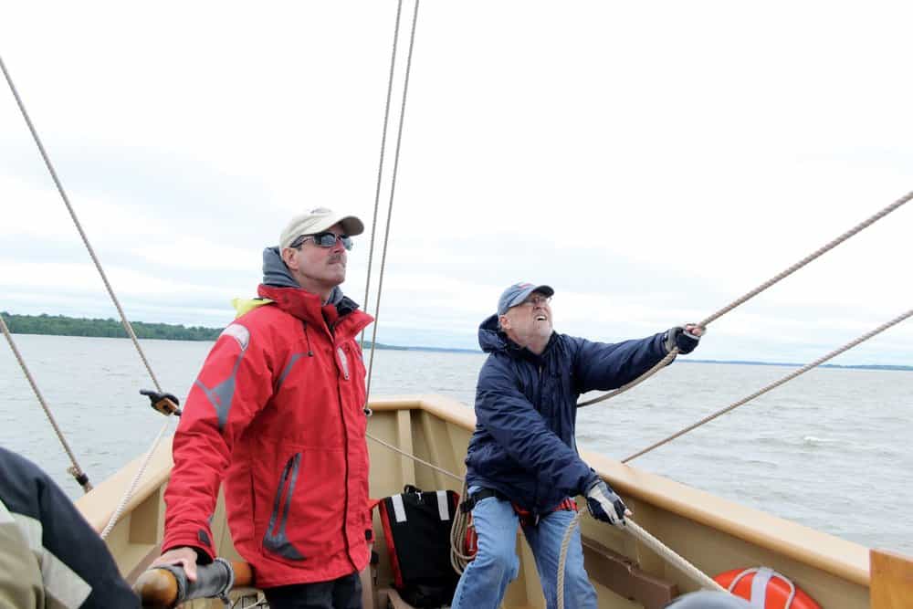  Captain Eric Speth (left) and volunteer Russ Sage (right) guide the 17th century replica vessel  Godspeed  along the James River.- photo Karen Soule 
