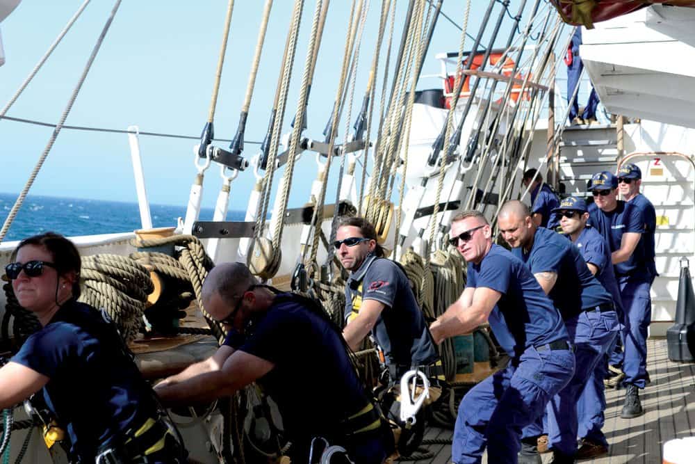   Justin Ailswoth (third from left) and Coast Guard crewmembers haul up one of the  Eagle ’s 23 sails.Photo by Karen Soule. 