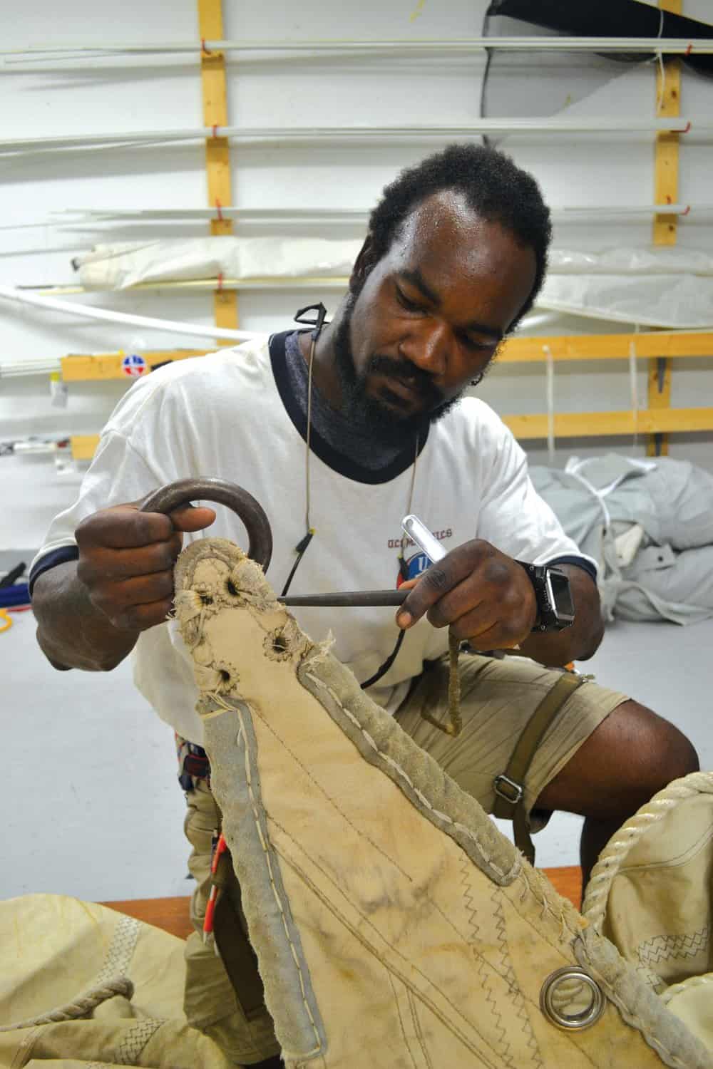  Dantes Chambre-Serres examines one of the  Eagle ’s old sails. Photo by Karen Soule. 